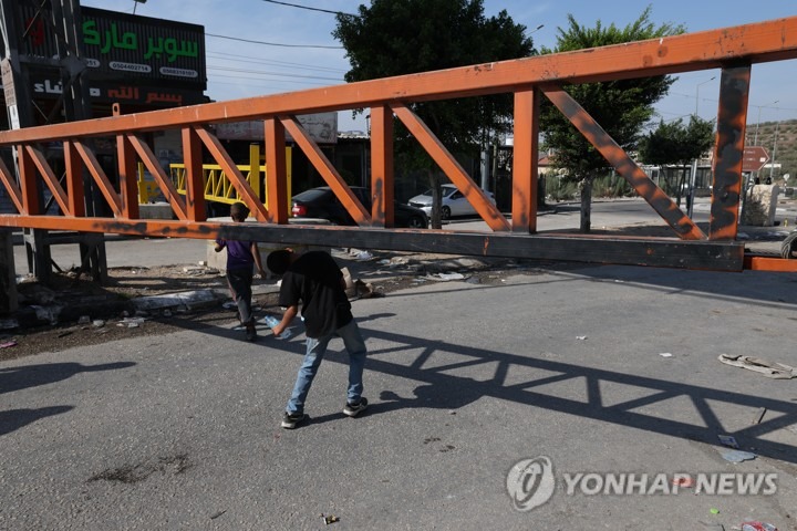 나블루스 입구 군 출입문 옆을 걸어서 지나는 팔레스타인 주민들